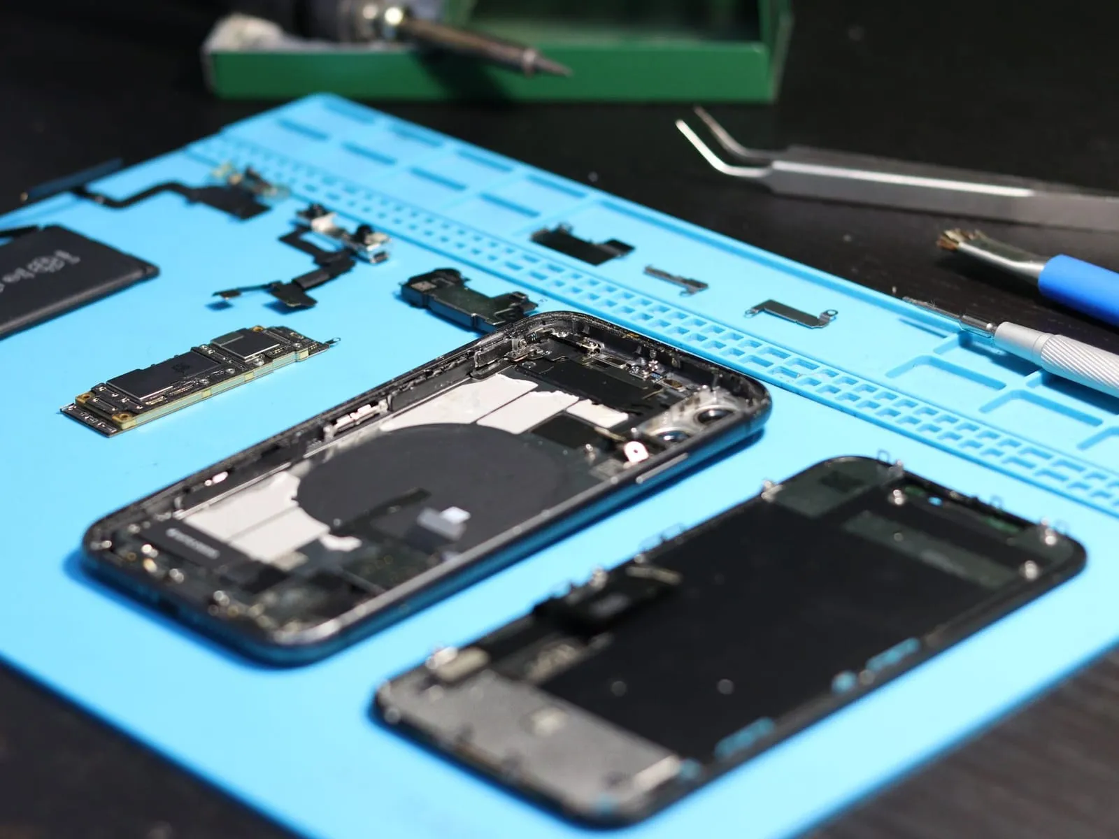 Rozłożony smartfon i narzędzia serwisowe na macie warsztatowej
