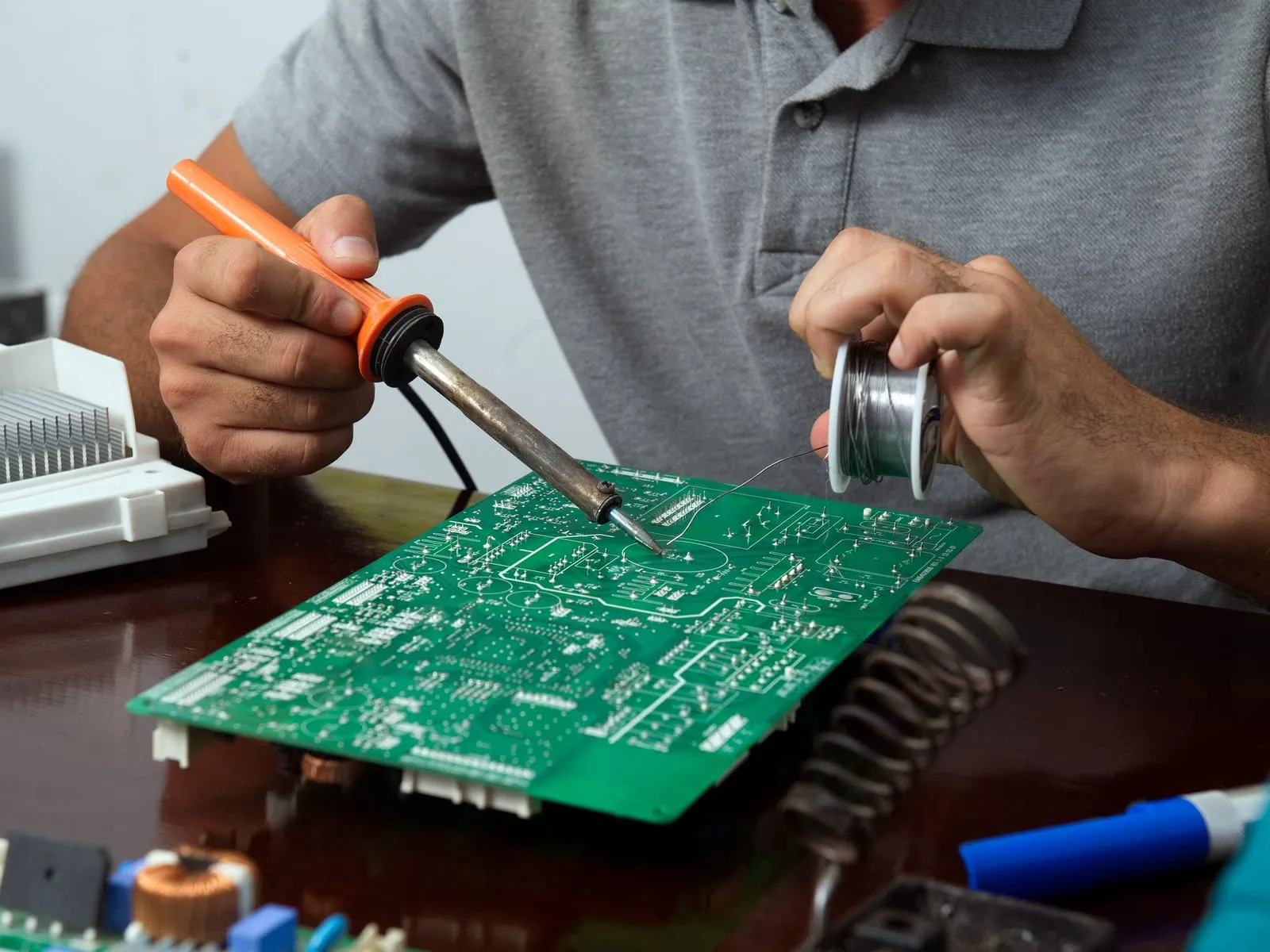 Serwisant lutuje płytkę elektroniczną na stole warsztatowym